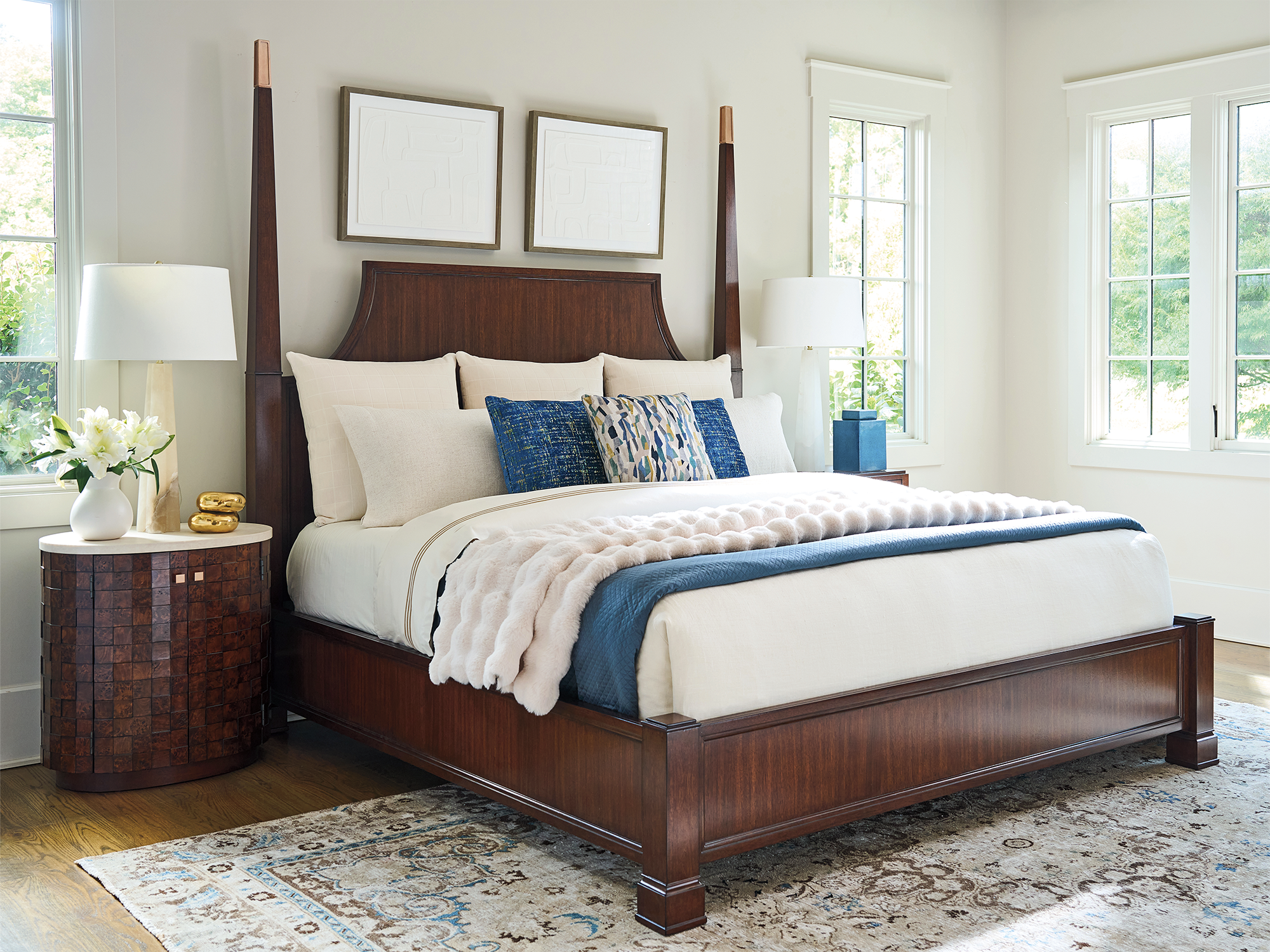 Lexington Rendezvous — sophisticated transitional bedroom featuring a dark cherry wood poster bed with rose gold accents, paired with a white-top nightstand with a faceted wood face and a traditional patterned rug.