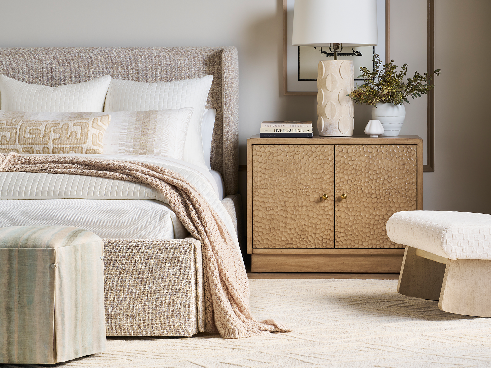 Vanguard Furniture — serene contemporary bedroom featuring the Medley King Bed with a dressmaker skirt, paired with the Virtuoso Rocker, a Manning Side Table, and a pair of Aubree Hexagon Waterfall Skirt Ottomans in a soft silver-blue fabric.