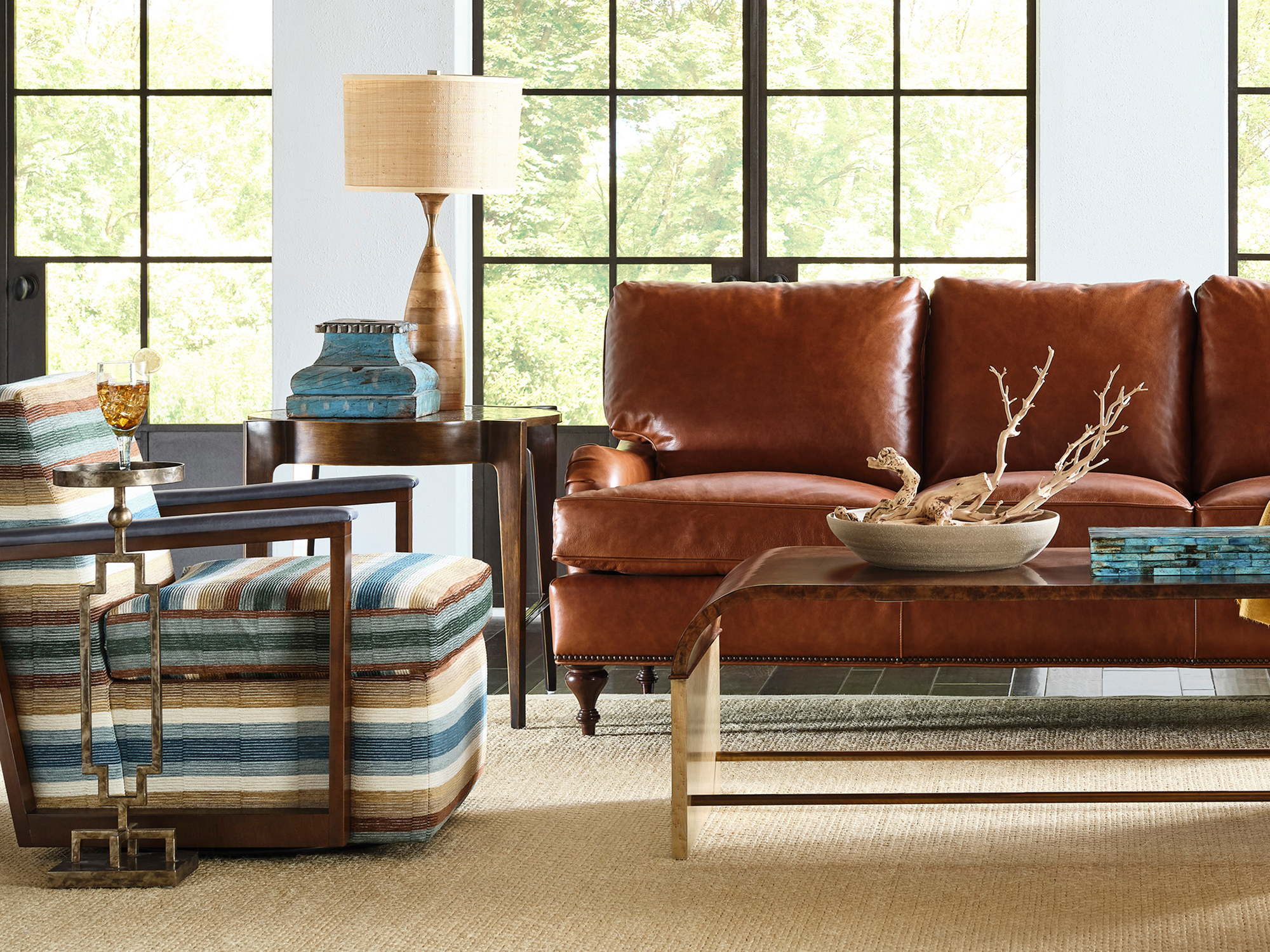 Hancock & Moore Your Way Classic — timeless luxury living room featuring a cognac leather sofa with nailhead trim, a vibrant multi-stripe accent chair, and a sleek waterfall coffee table.