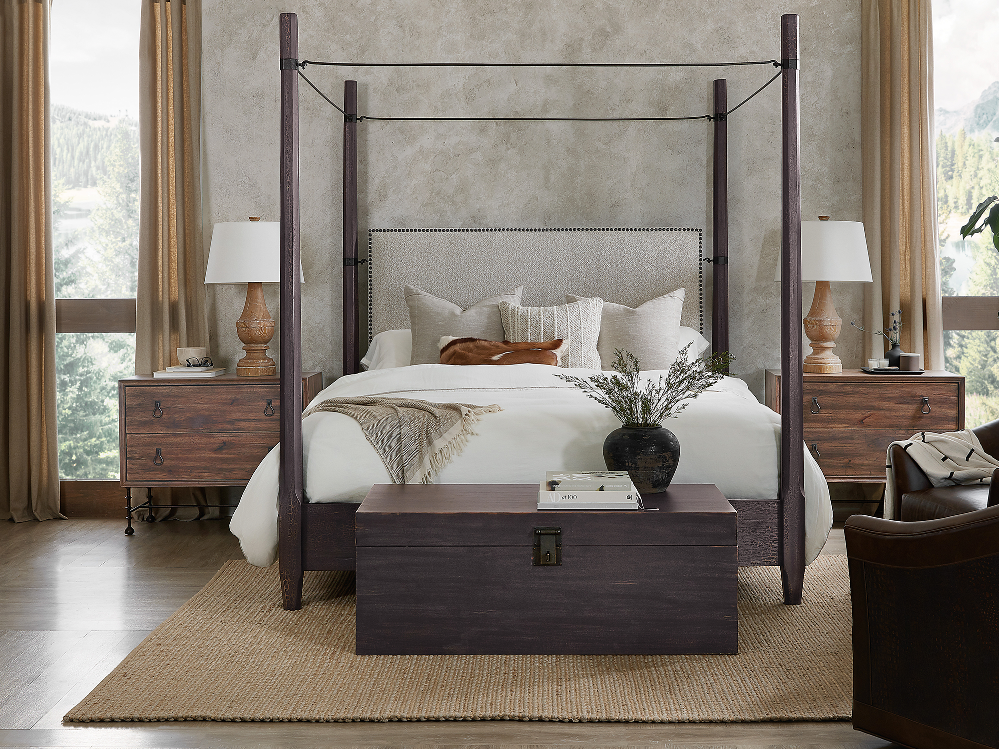 Hooker Furniture Big Sky — rugged lodge-inspired bedroom featuring a dark-charcoal four-poster canopy bed with wire-tension details, a matching storage trunk, and warm oak nightstands.