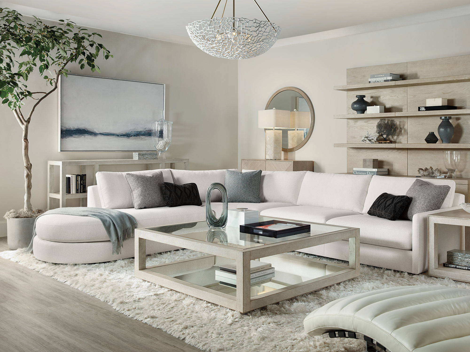 Hooker Furniture Cascade — ethereal modern living room featuring a sprawling cream sectional with a curved chaise, a glass-top tiered coffee table, and soft champagne-finished oak accents.