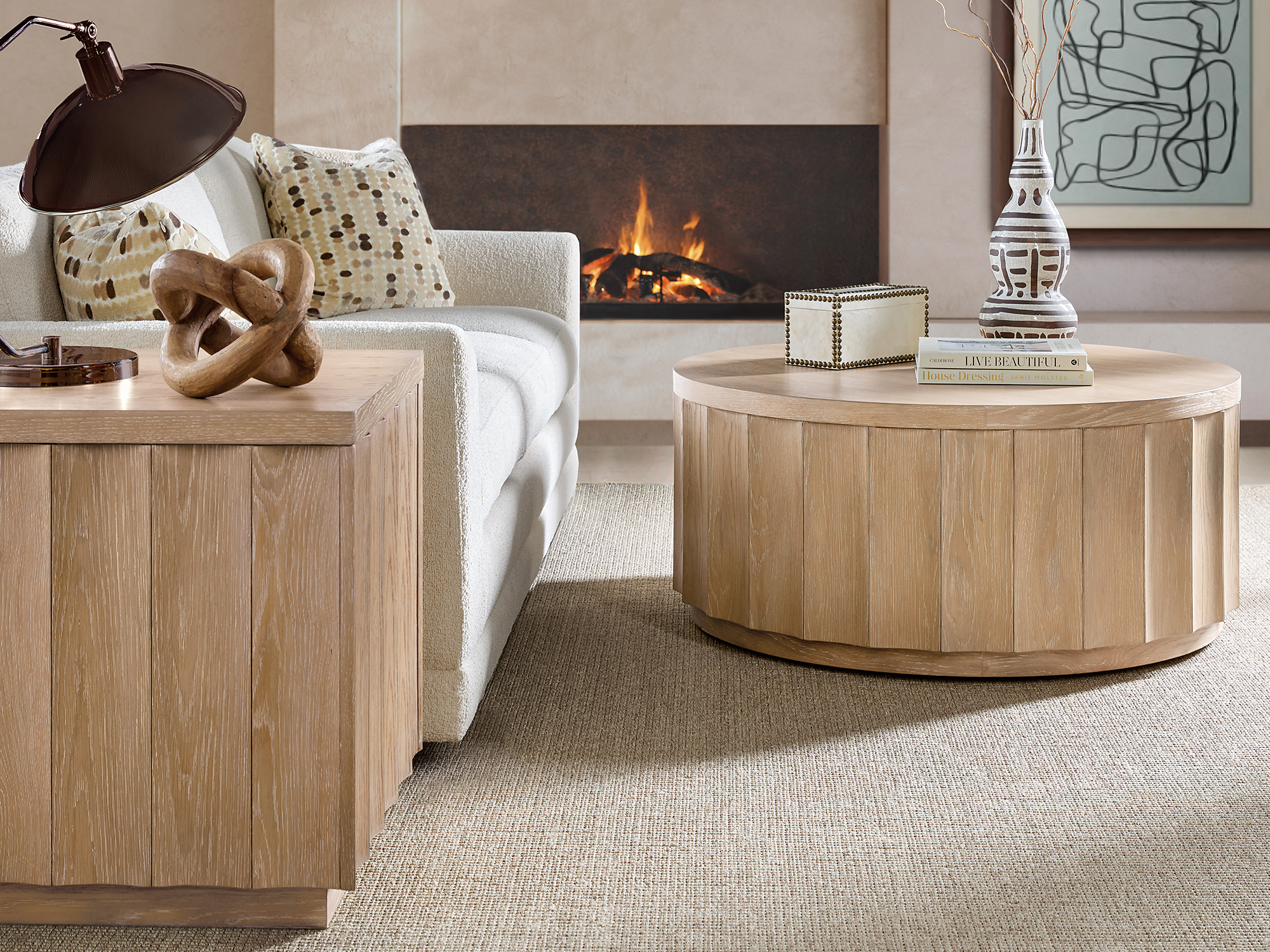 Hooker Furniture Commerce & Market — organic modern living room vignette featuring a fluted white oak drum coffee table, matching end table, and a cream bouclé sofa by a minimalist fireplace.