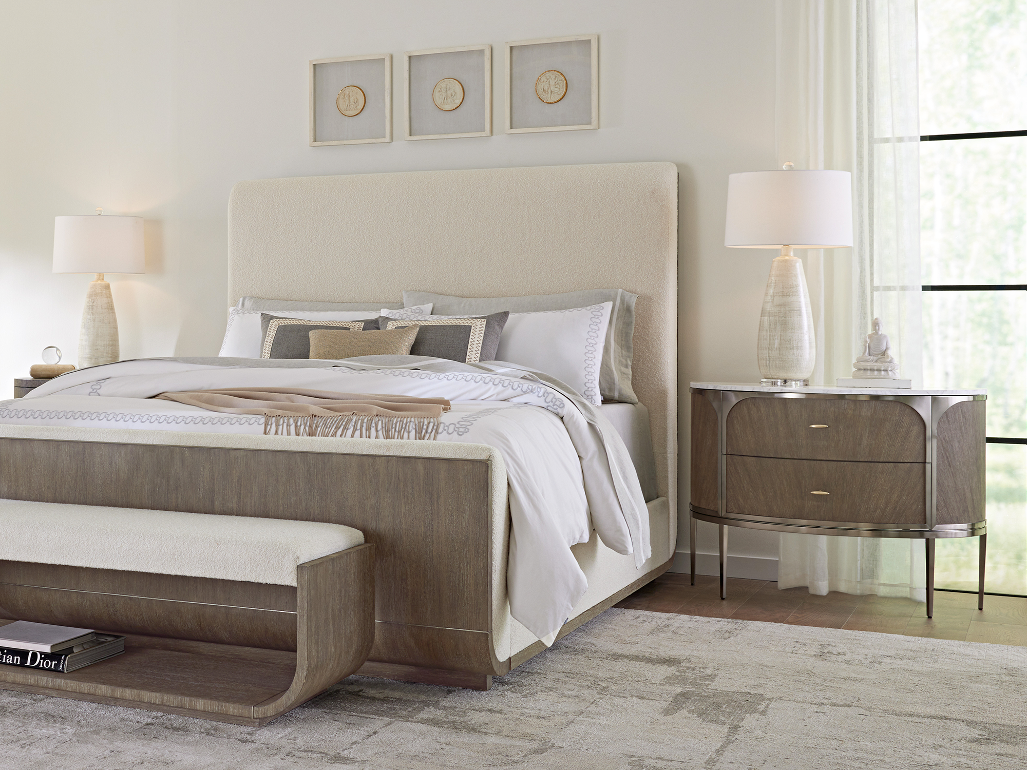 Hooker Furniture — Modern Mood collection contemporary bedroom featuring a cream bouclé upholstered bed with wire-brushed oak trim, a matching curved bed bench, and a marble-top bachelor's chest.
