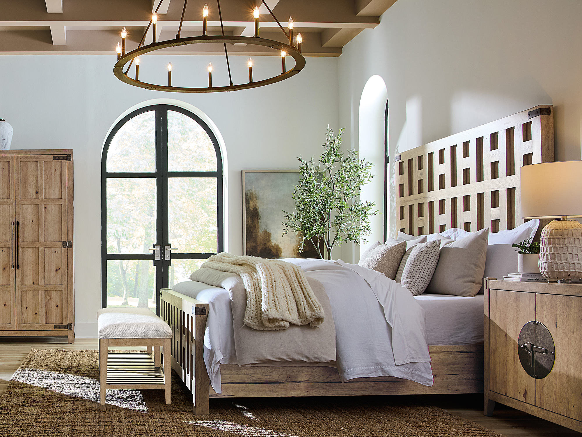 Hooker Furniture Vineyard Row — rustic Mediterranean bedroom featuring an oversized grid-patterned wood headboard, a round wagon wheel chandelier, and a light-oak bachelor's chest with a decorative iron latch.