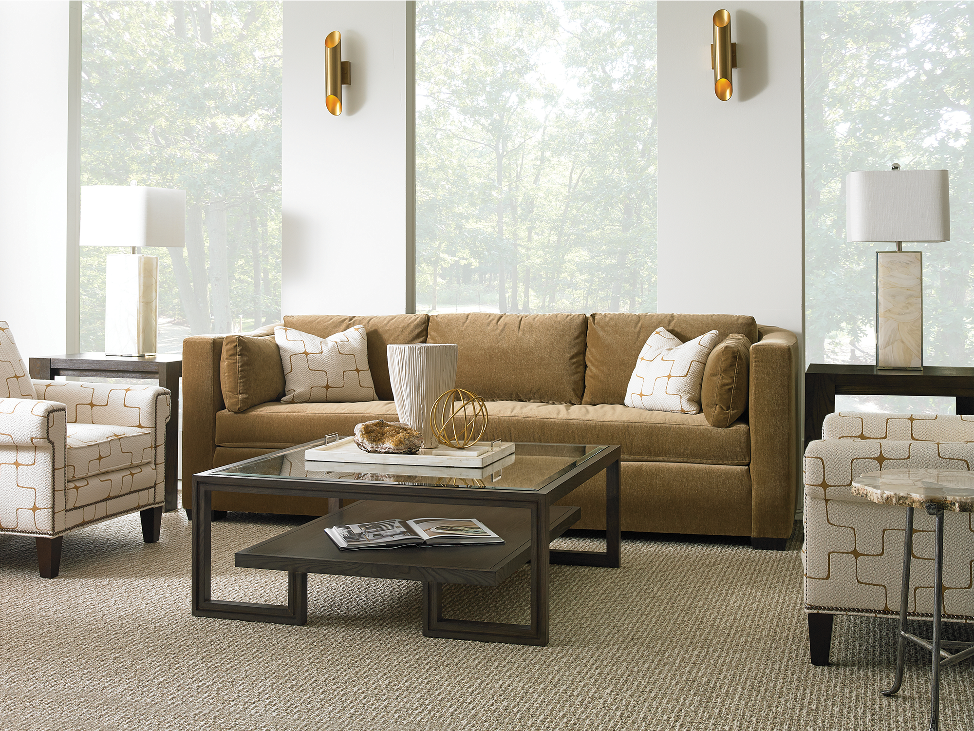 Sherrill Furniture — elegant living room featuring a mustard-gold velvet sofa with clean lines, paired with cream armchairs in a gold geometric pattern and a tiered, dark-wood glass-top coffee table.