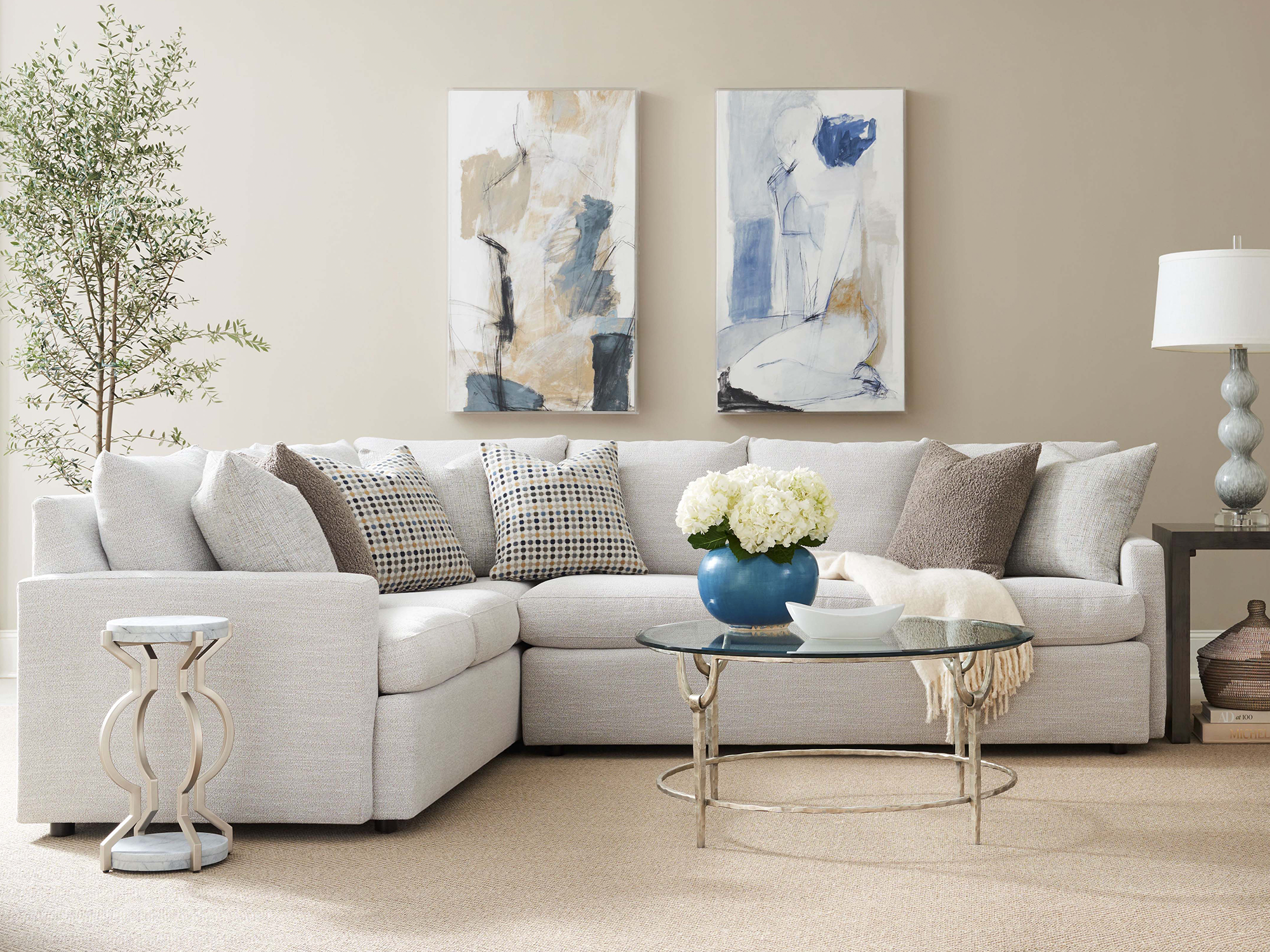 Sherrill 41 Series — Light gray textured L-shaped sectional with track arms in a transitional living room. Features a silver-leaf glass-top cocktail table and a sculptural marble-top drink table in a bright, neutral-toned gallery space.